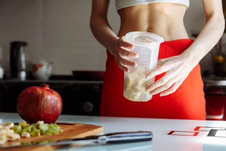 A lady is cooking a banana milkshake in the kitchen. Close up view of handsの写真素材