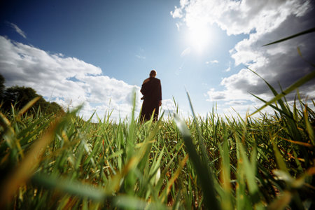 Blurred lady in black dress is standing in the middle of green field. Sunny day.の写真素材