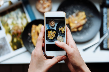 Woman taking a photo of breakfast with smartphone, hands hold phone, frome aboveの写真素材
