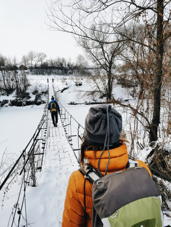 Hiking tourist is standing before the river with a bridge. Winter Viewの写真素材
