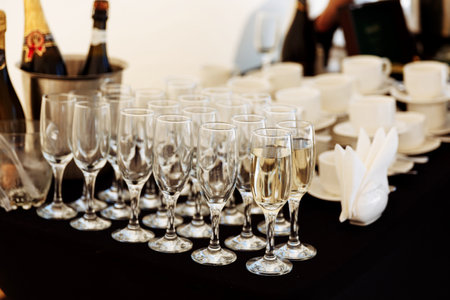 A row of glasses partially filled with champagne are lined up prepearing to be servedの写真素材