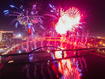 Drone flight above colorful fireworks on the black sky background over-water.