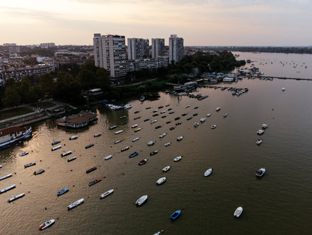 Paddle boarders and kayakers on the Sava River at sunset with Belgrade skyline in background.の写真素材
