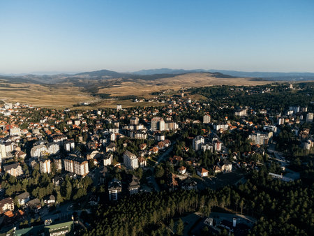 Aerial view of Zlatibor, Serbia, showing residential buildings and vast mountain landscape under clear sky. g.の写真素材