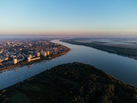 Aerial sunrise view over Belgrade city, river bend and urban skyline at golden light. g.