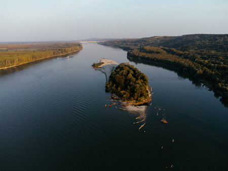 Aerial view of a serene river island at sunset, surrounded by lush forest. g.