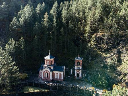 Orthodox church in Tara mountains forest with sunlight and stone bell tower in Serbia. g.