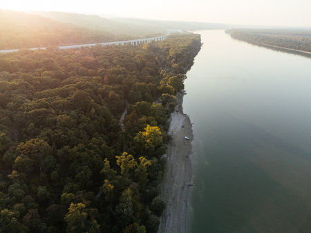 Aerial view of a serene river island at sunset, surrounded by lush forest. g.