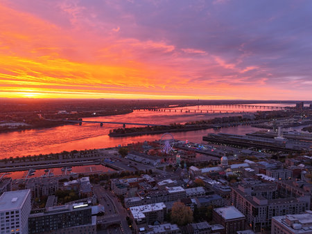 Vibrant sunset over Montreal skyline with St Lawrence River and La Grande Roue reflecting colorful...