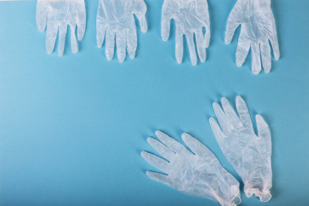 White surgical gloves are isolated on the blue background. The concept protects against infection or contaminationの写真素材