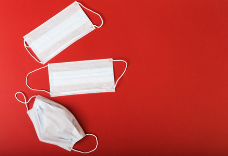 Three medical masks are on isolated red backgroundの写真素材