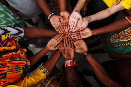 Palms up hands of a group of multinational people: African, Latin American and European people which stay together in a circle.の写真素材