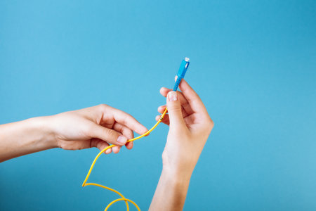 Woman's hands hold SC and FC connector fiber optic patch cord single mode on blue backgroundの写真素材