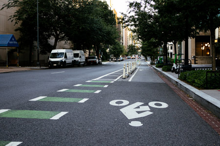 Protected urban bike lane along city street with bollards and cycling arrows. g.