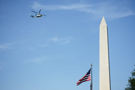 Helicopter flying near to Washington Monument framed by trees near water, dedicated to George Washington, under clear summer sky. g.の写真素材