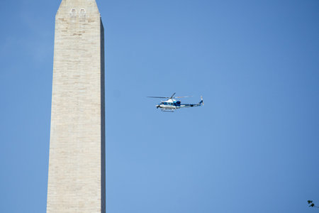 Helicopter flying near to Washington Monument framed by trees near water, dedicated to George...