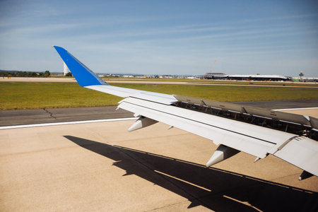 Airplane wing view during taxiing on airport runway under clear blue sky on a sunny day. g.