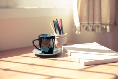 Cup of coffee and a book on a wooden tableの写真素材