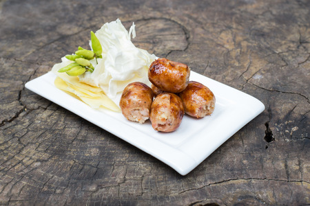 Thai grilled sausage with vegetable on old woodの写真素材