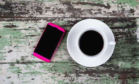 Coffee cup and smartphone on old wooden  tableの写真素材