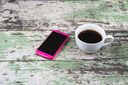 Coffee cup and smartphone on old wooden  tableの写真素材