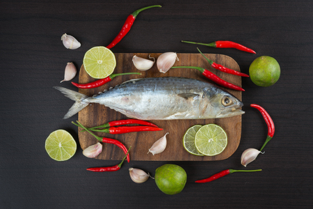 Raw salt mackerel fish with vegetables on wood tableの写真素材