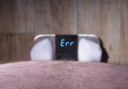 Hairy, obesty man standing in front of a wighting scale indicating error