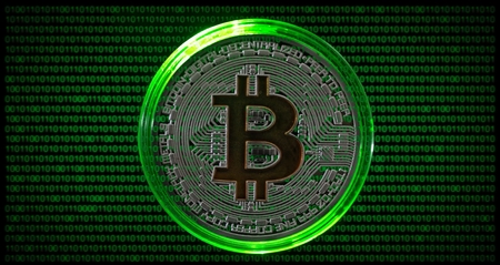 Physical coin with bitcoin symbol on green binary code backgroundの写真素材