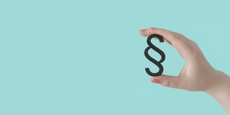Woman hand hold a paragraph icon in front of blue background. Panoramic image with copy space.