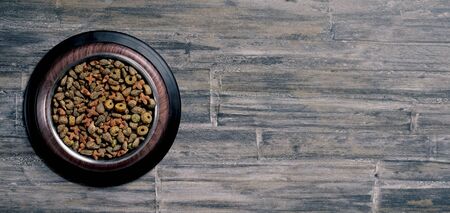 Bowl with dry food for pets on wooden background. Panoramic image with copy space.の写真素材
