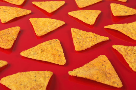 Pattern of tortilla chips on a red background.