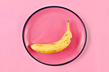 Overripe banana on a pink plate. Nutritional concept.の写真素材