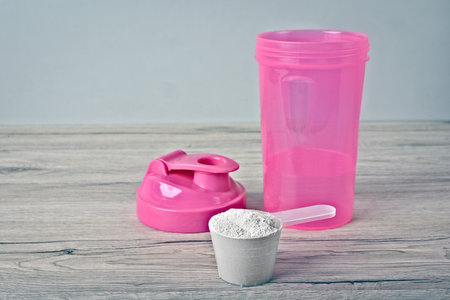Protein shaker next to protein powder in a scoop,の写真素材