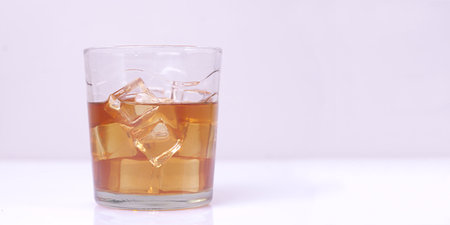 Close-up of glass with drink and ice cubes against white background. Panoramic image with copy spaceの写真素材