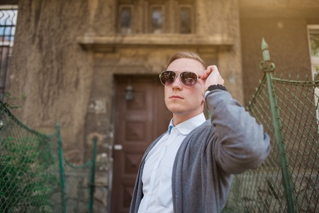 Portrait of young stylish man with glasses walking on the street of old cityの写真素材
