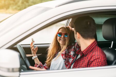Couple sitting in the car listening to music and having fun. Enjoy a fun journeyの写真素材