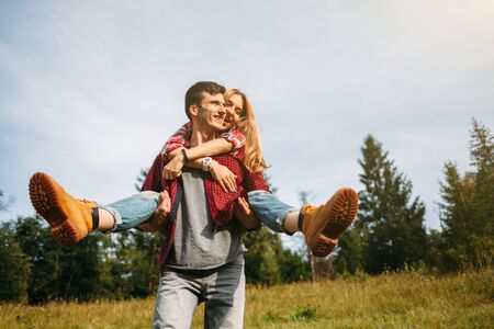 Portrait of a man carrying a woman in his arms and smiling. Travelers couple good time in the mountainsの写真素材