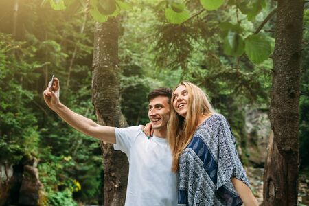 Beautiful young couple exploring in the park and makes selfieの写真素材