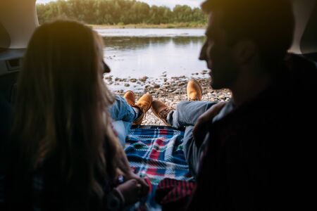 Portrait of a couple by their car before hiking, back view of the riverの写真素材