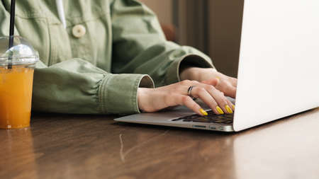 Close Up of Unrecognizable Woman Working on Laptop at a Cafe Table, Female Student Using Her...