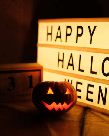 Head Jack Pumpkin with Scary Smile and Burning Candles for Party Night, 31 October and Tablet with Text Happy Halloweenの写真素材
