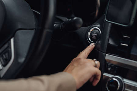 Woman Holding Finger on a Button to Start or Stop Engine of the Modern Car