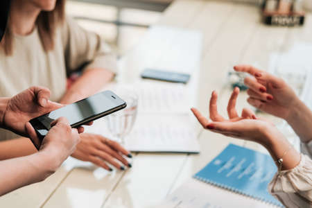 Close Up of Female Hands at Table, Two Women Making Order to Waiter with Smartphone in the...