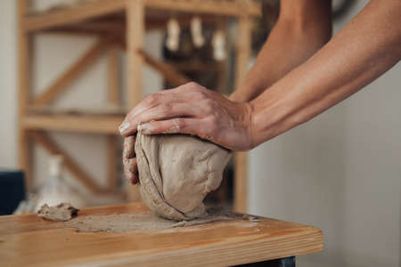 Unrecognisable Potter Master Preparing Pile of Clay to Creating Pot on a Pottery Wheel in Ceramic...