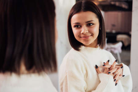 Young Caucasian Woman Admiring Herself in the Mirror in Hallway of the Beauty Salonの写真素材