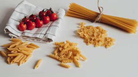 Different Types of Pasta and Cherry Tomatoes on the Kitchen Tableの写真素材