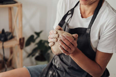 Unrecognisable Female Potter Master Preparing Pile of Clay to Creating Pot on a Pottery Wheel in Her Ceramic Studioの写真素材