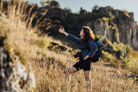 Travel Young Woman with Backpack and Camping Mat and Wearing Digital Camera on a Strip and Showing...