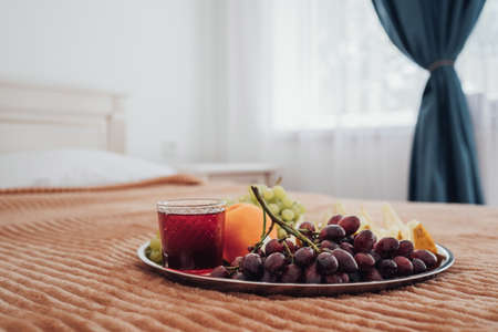 Tray of Fruit and Glass of Juice Laying on the Bed in Hotel Room