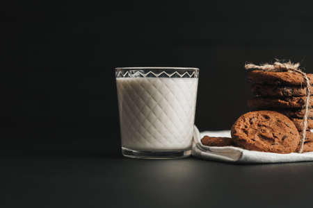Glass is Filled with Milk and Homemade Cookies on the Black Tableの写真素材